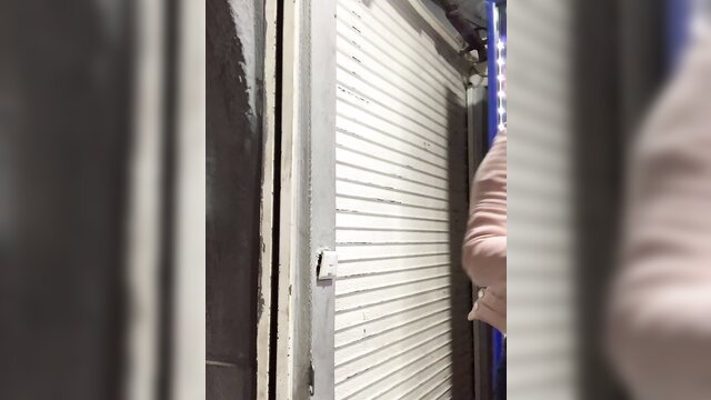 Sara Luna by garage shutter in pink top, teasing pose