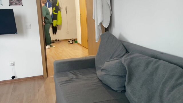 Ethan Lestray in green hi-vis vest by door in cozy apartment scene
