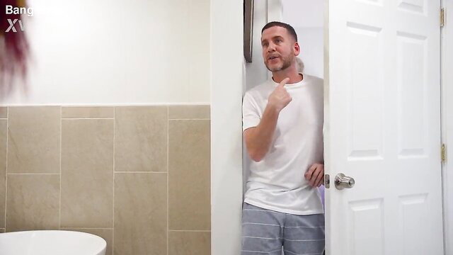 Hot male roommate in white tee and gray sweats stands by open bathroom door