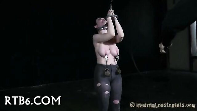 Bondage slut bound with chains, collared, tits exposed in BDSM restraint