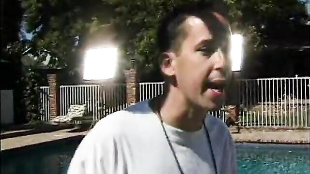 Slim brunette guy shouting outdoors by pool in white shirt