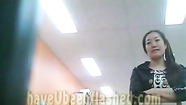 Asian woman with ponytail smirks arms crossed in office