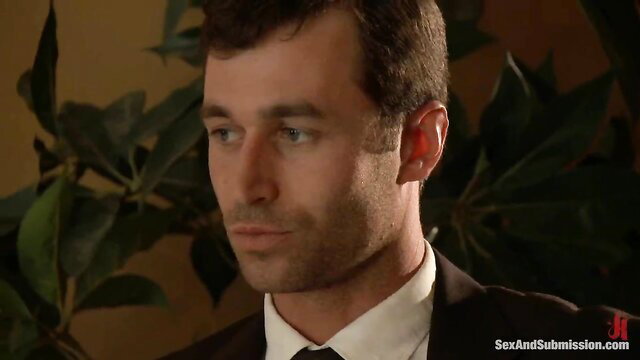 Handsome suited man with intense gaze in BDSM submission scene