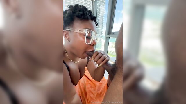 Ebony babe with glasses sucking big black cock by window