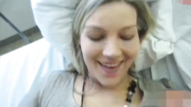 Itty Bitty smiling in bed, blonde hair, gray top, amateur vibe