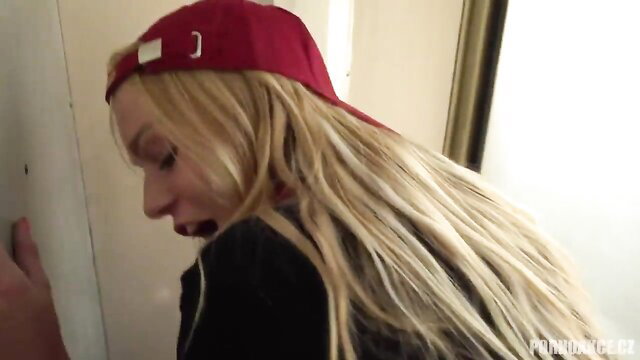 Blonde in red cap leans against wall, close-up face and hand on door