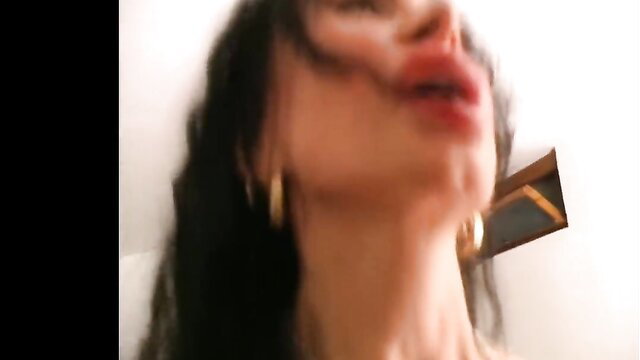 Closeup of aroused trans woman with glossy lips, heavy makeup, gold hoops