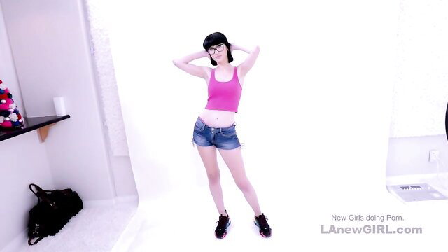 Asian newgirl in pink tank top and denim shorts poses sexy solo