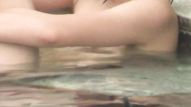 Beautiful Asian babe nude in steamy outdoor bath, wet skin glistening