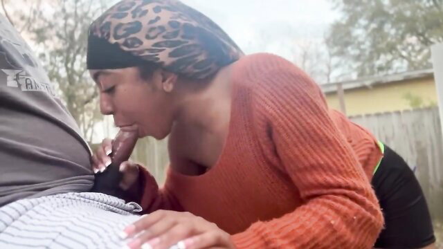 Petite black babe in leopard headwrap sucks cock outdoors, orange sweater