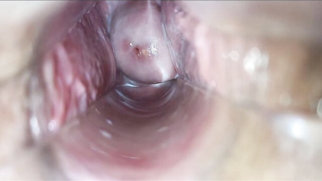 Close-up speculum view of wet pink pussy with yellow discharge in lesbian orgasm video