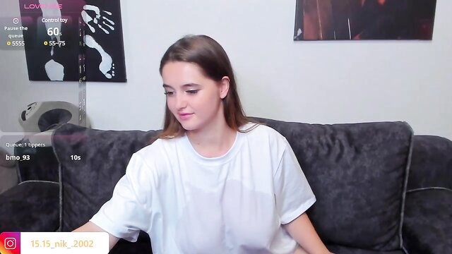 Cute brown-haired teen girl smiling on cam in oversized white tee