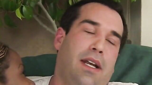 Man with eyes closed in ecstasy as ebony girl with pigtails pleasures him on sofa