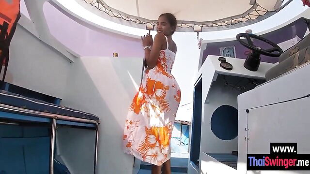 Petite Asian teen in orange floral dress twerking big ass on boat deck