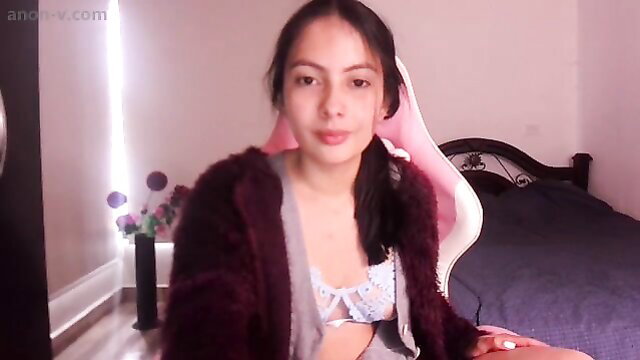 Hot Latina in pink lingerie sits on gaming chair, teasing cleavage