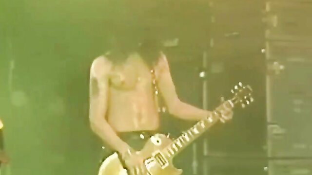 Shirtless long-haired rockstar Axl Rose lookalike shredding guitar on stage