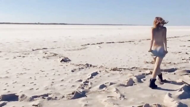 Blonde teen walks nude on vast salt flat beach in tiny denim shorts
