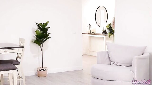 Alexis Malone in bright white bedroom with plant and chair