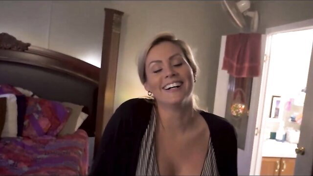 Coco Vandi smiling busty MILF in open cardigan on bed