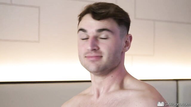 Hot muscular guy with buzzcut smirking shirtless in steamy shower scene