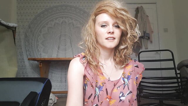 Sydney Harwin in pink bird dress, blonde hair smiling seductively