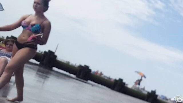 Saucy babe struts city beach in colorful bikini, toned body