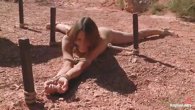 Nude Amber Rayne bound spread eagle outdoors in desert bondage scene
