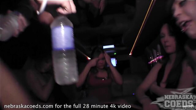 Party girls in car chug neon drinks, wild night vibe