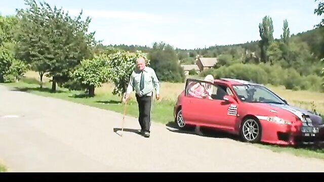 Grandpa with cane walks by red sports car door open in outdoor setting