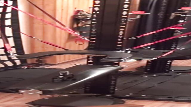 Aris Dark bound in BDSM dungeon on kink rack