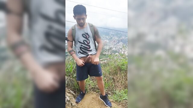 Tattooed Latino guy flashing bulge in Nike tank and shorts on mountain hike