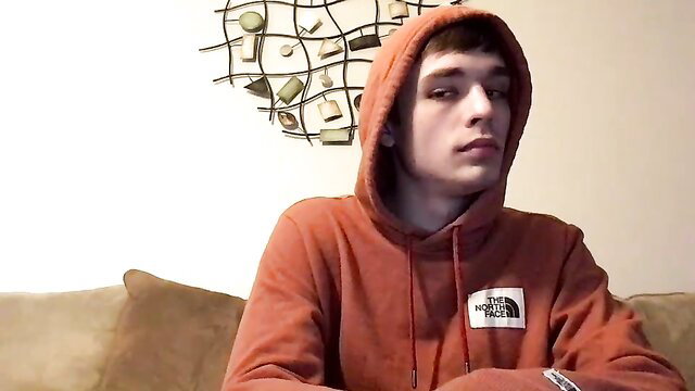 Young Latino twink in orange hoodie, intense gaze, gay amateur thumbnail