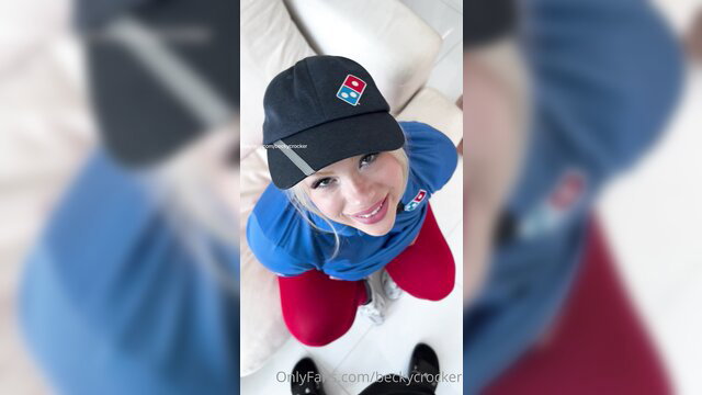 Cute blonde Domino's pizza delivery girl in uniform hat smiling down at viewer