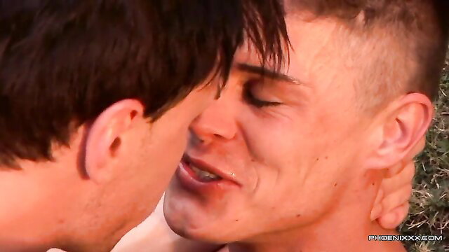 Two fit young men passionately kissing outdoors in hot trans sex scene