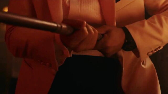Gal Gadot in tight orange suit gripping long rod in Red Notice hot scene