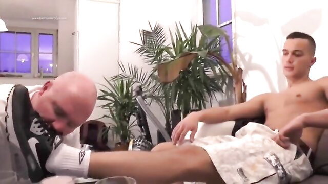 Bald man munching nuzzling Nike sneaker on fit white twink's white socked foot