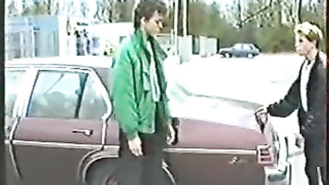 Vintage gay men in leather jacket outdoors by car, 80s style