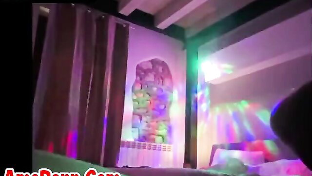 Exotic girl in vibrant bedroom with rainbow lights and purple curtains