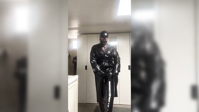 Shiny black PVC trenchcoat and hood fetish model posing seductively