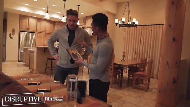 Young Asian actor chats with fit white star holding box in kitchen