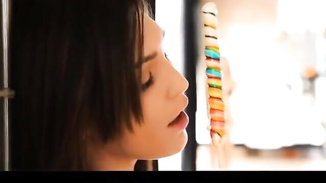 Holly Michaels closeup profile gazing at colorful lollipop