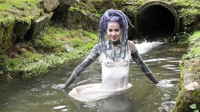 Anuskatzz in wet white dress by stream, sensual tattooed model