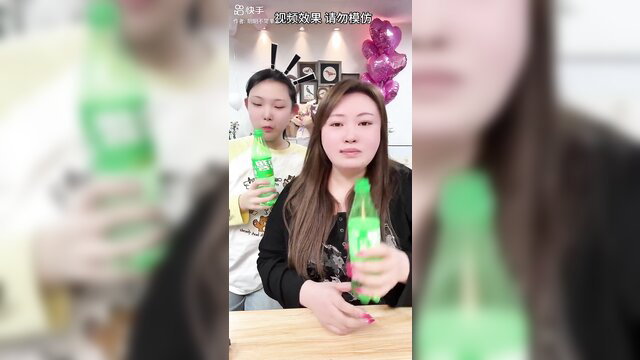 Two Chinese girls holding green bottles, pouting faces in vomit fetish preview