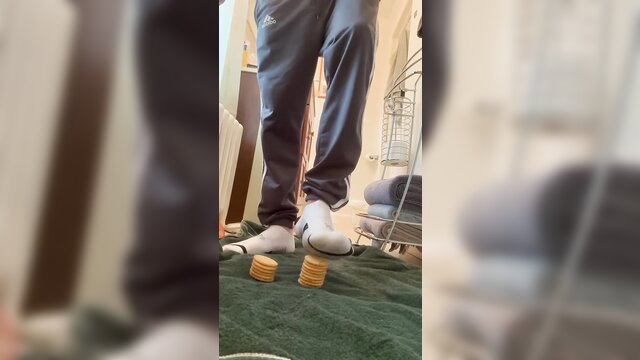 Giant feet in white socks crushing crackers on floor closeup