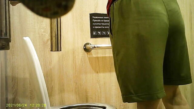 Spy cam of thick white woman's big ass in green shorts at public toilet