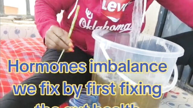 Indian woman in pink hoodie pours water from bucket for gut health vomit fix