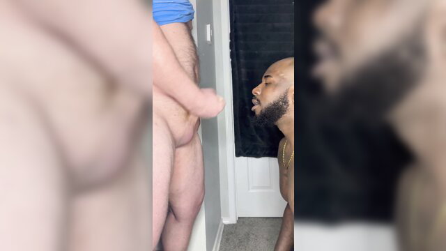 Black man kneeling sucks white guy's cock in amateur bathroom BJ