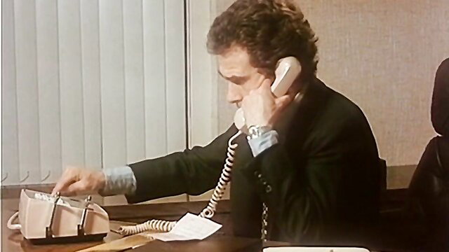 Man in suit on retro phone at desk in office scene