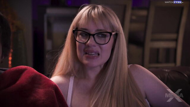 Blonde Jessica Ryan in glasses smirking seductively on couch