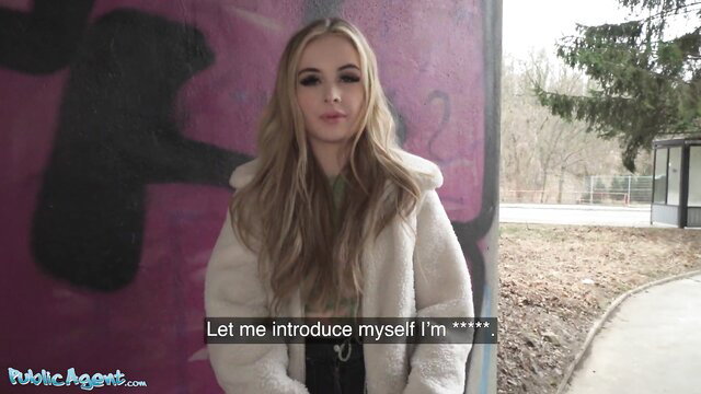 Blonde English tourist in fluffy coat smiles at camera in outdoor public spot